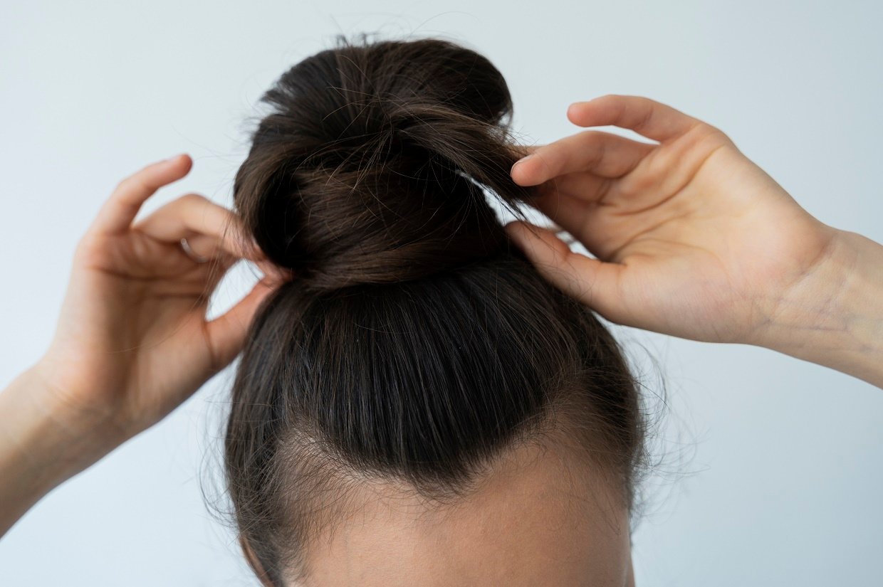 high-angle-woman-arranging-messy-bun